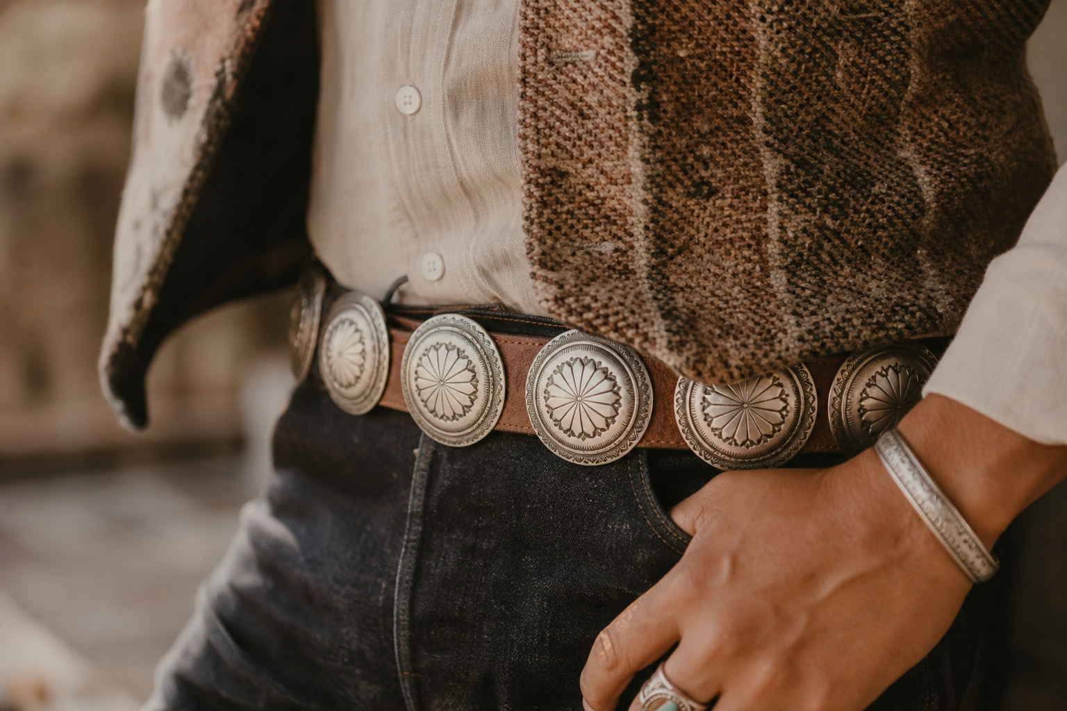 Série de conchos ronds en métal argenté disposés sur une ceinture en cuir brun — style Navajo classique